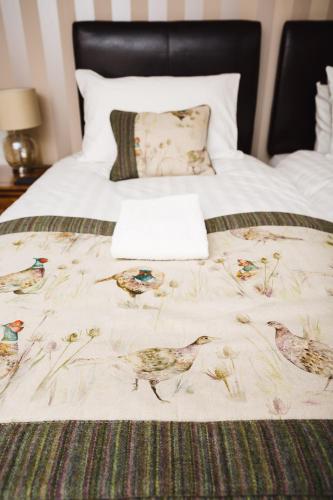 a bed with a blanket with birds on it at Glen Clova Hotel & Luxury Lodges in Millton of Clova
