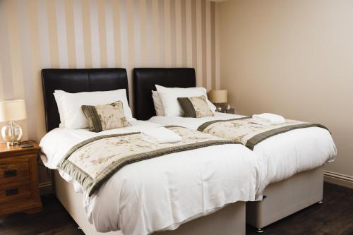 two beds with white sheets and pillows in a bedroom at Glen Clova Hotel & Luxury Lodges in Millton of Clova