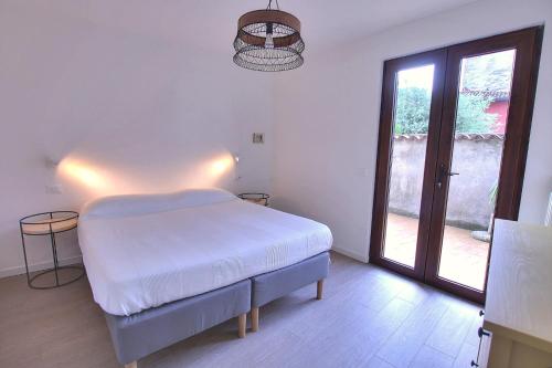 a white bedroom with a bed and a large window at La Briciola in Sirmione