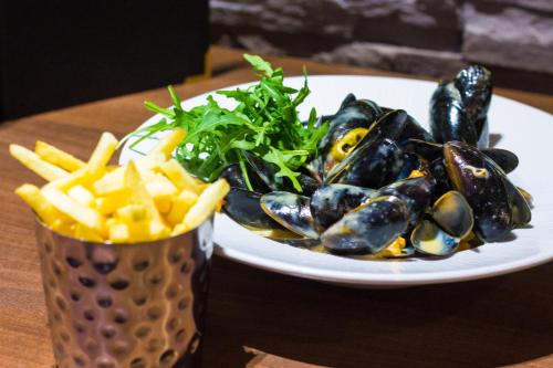 a plate of mussels and french fries on a table at The Parkville Hotel in Hamilton