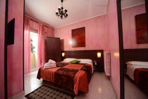 ein rosafarbenes Schlafzimmer mit einem Bett und einem Fenster in der Unterkunft Hotel Okinawa in Rimini