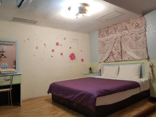 1 dormitorio con 1 cama con sábanas moradas y flores en la pared en San Ho Hotel, en Taoyuan