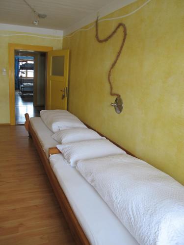 a row of white beds lined up against a wall at Schiff Bihlerdorf - Hostel in Bihlerdorf