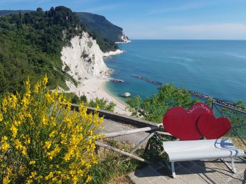 two hearts sitting on a bench overlooking a beach at Viverenumana in Numana
