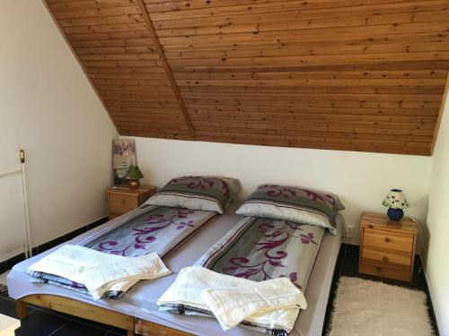uma cama num quarto com tecto em madeira em Orchidea Vendégház - Zebegény em Zebegény