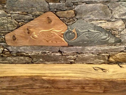 a wooden fish on the side of a stone wall at Delfin Dal Pianhol in Casteldelfino