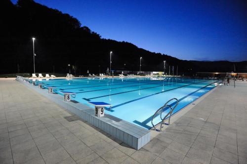 uma grande piscina iluminada à noite em Rooms Kozmus em Brestanica