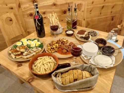 a wooden table with plates of food and a bottle of wine at Delfin Dal Pianhol in Casteldelfino