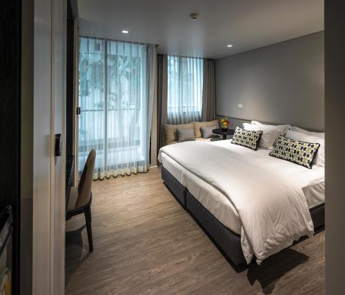 a bedroom with a large bed and a large window at Apartelle Jatujak Hotel in Bangkok