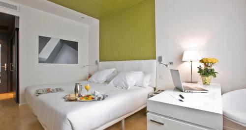 a bedroom with a white bed with a laptop on it at Hotel Zentral Castellana Norte in Madrid