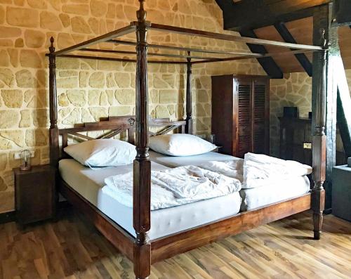 1 dormitorio con cama de madera y almohadas blancas en Fewo GERICHTSSTUBE im Rittergut bei Dresden für 2 Erw und 4 Kids, en Wachau