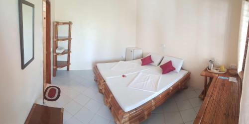 a bedroom with a bed with white sheets and pink pillows at Divers Lodge Moalboal in Moalboal