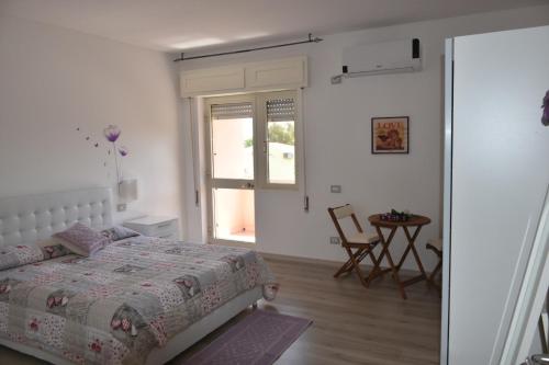 a bedroom with a bed and a table and a window at Sa Mariposa in Muravera