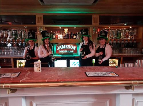 a group of women in green hats standing behind a bar at The Parkville Hotel in Hamilton