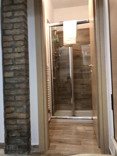 a bathroom with a glass shower and a brick wall at Arco dolce Arco in Benevento