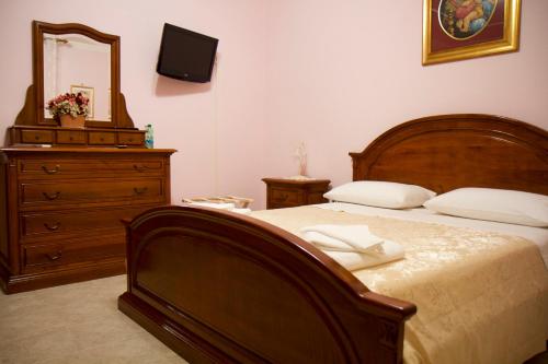 a bedroom with a bed with a dresser and a mirror at Domus Palombi in Ladispoli
