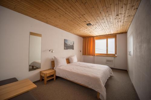 a bedroom with a large bed with a wooden ceiling at GALAAXY Mountain Hostel in Laax