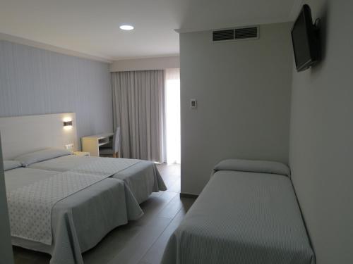 a hotel room with two beds and a television at Hotel La Lanzada in A Lanzada