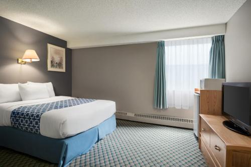 a hotel room with a bed and a flat screen tv at Travelodge by Wyndham Edmonton Airport in Leduc