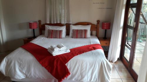 a bedroom with a bed with a red and white blanket at Jacaranda Guesthouse in Eshowe
