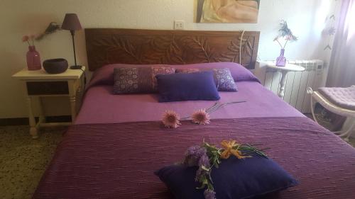 Una cama púrpura con almohadas y flores. en Fonda Felip en Port de la Selva
