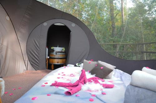 un lit dans une tente noire avec des animaux farcis roses dans l'établissement Sphair perchée, à Fisenne