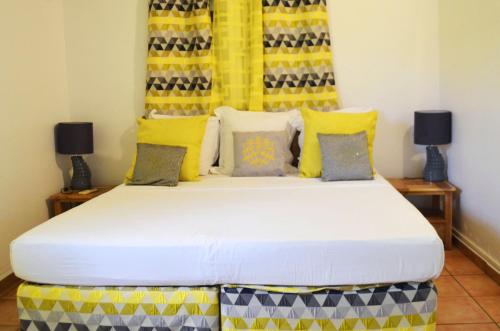 a bedroom with a large bed with yellow and blue pillows at Jericho Gites & Spa in Capesterre