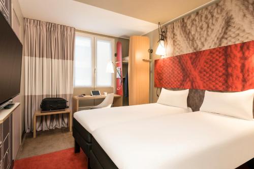 パリにあるイビス ガール デュ ノール シャトー ランドン 10 エムの大きなベッドとデスクが備わるホテルルームです。