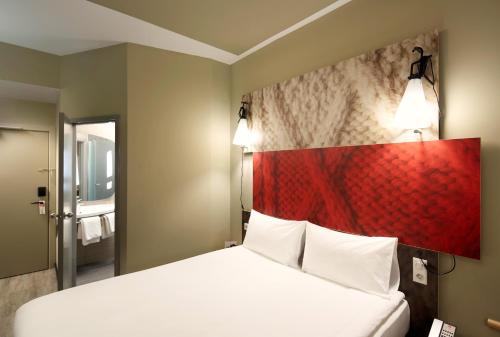 a bedroom with a large bed with a red headboard at ibis Paris Gare du Nord Château Landon 10ème in Paris