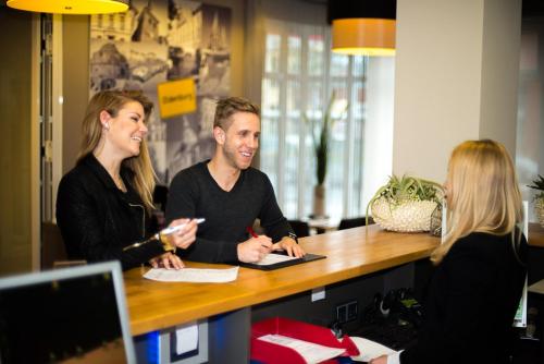 a man and two women sitting at a desk at Hotel Sprenz in Oldenburg