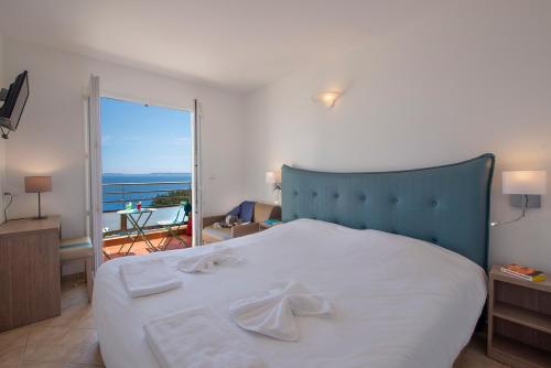 a bedroom with a large bed with towels on it at Hôtel-Club du Domaine d'Aiguebelle, USSIM Vacances in Le Lavandou