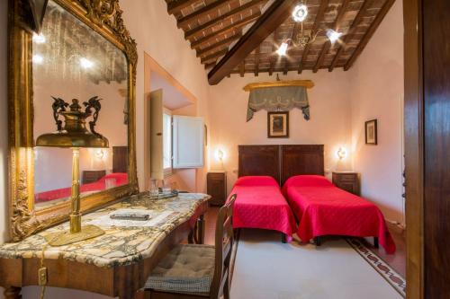 Cette chambre comprend 2 lits rouges et un miroir. dans l'établissement Residenza alla Lizza, à Sienne