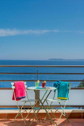 a table and two chairs on a balcony with the ocean at Hôtel-Club du Domaine d'Aiguebelle, USSIM Vacances in Le Lavandou