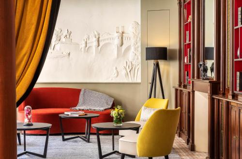 a living room with a red couch and yellow chairs at Hotel Ducs de Bourgogne in Paris