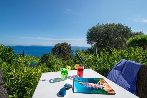 a table with a laptop on it with a view of the ocean at Hôtel-Club du Domaine d'Aiguebelle, USSIM Vacances in Le Lavandou