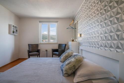 a bedroom with a bed with two chairs and a window at Villa Jidro in Trogir