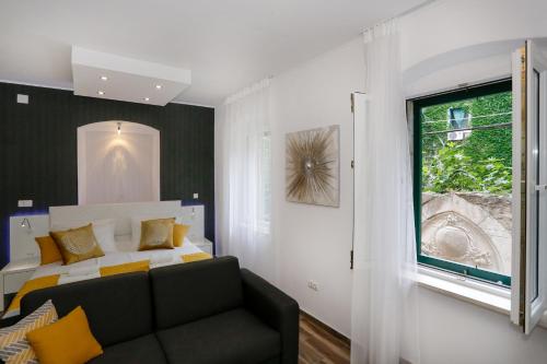 a bedroom with a bed and a couch and a window at Studio Apartman Fictilis in Split