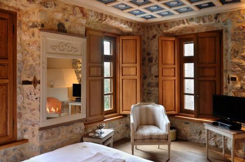 - une chambre avec un lit, une chaise et une télévision dans l'établissement Archontiko Chioti, à Leonidio