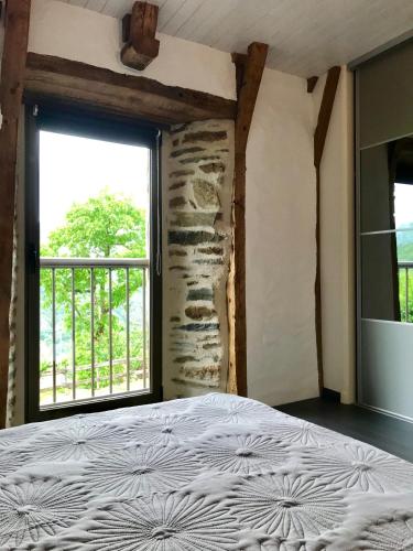 une chambre avec un lit et une grande fenêtre dans l'établissement LA PERLE DE LA VALLÉE, à Vallon