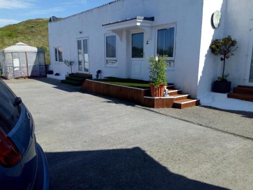 a car parked in front of a white house at Gumtree Cottage in Port Askaig