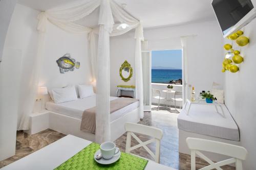 a white bedroom with a bed and a view of the ocean at Sol Mare Salis in Kamari
