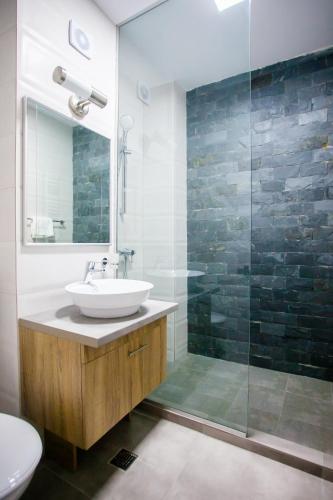 a bathroom with a sink and a glass shower at Lira Holiday Apartments in Eforie Nord