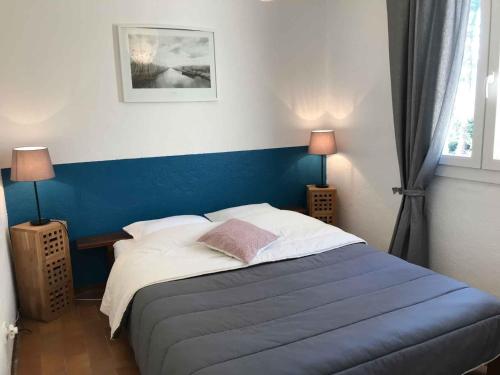 サン・ジャン・デュ・ガルにあるVillage de gîtes Ravelのベッドルーム1室(ブルーヘッドボード付きのベッド1台付)