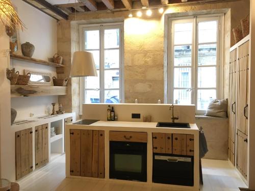 ボルドーにあるMirmont Greek Styleのキッチン(木製キャビネット付)、大きな窓が備わります。