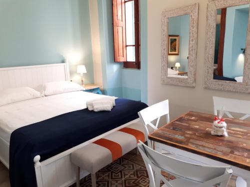 1 dormitorio con cama, mesa y espejos en Sofia Family Suites en Carloforte