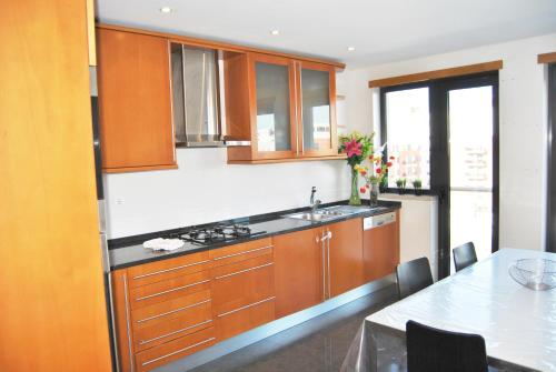 a kitchen with wooden cabinets and a sink and a table at Parque Nacoes Prime Apartments 16 - 3 quartos in Lisbon