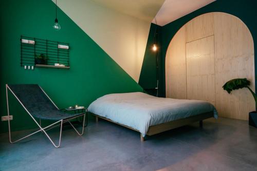 een groene slaapkamer met een bed en een stoel bij Boutique B&B Graaf in Gent