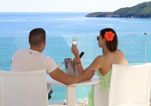 a man and woman sitting at a table with a glass of wine at Shine residence in Budva