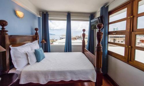 a bedroom with a bed and a large window at Hotel l'Impératrice in Fort-de-France