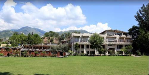 a large apartment building with a large grass field at Neelum View Hotel in Muzaffarabad